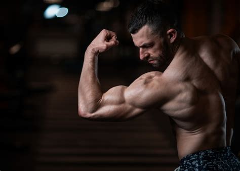 Homme Sportif Avec Un Corps Musclé Pose Dans La Salle De Gym Exhibant Ses Muscles Photo Premium