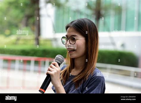 Female Journalist With Microphone Standing Against Building Stock Photo