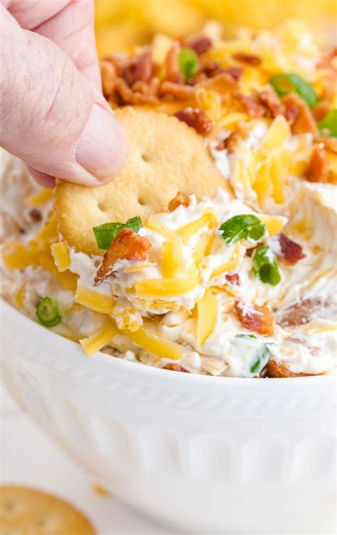 Close Up Shot Of A Ritz Cracker Being Dipped In A White Bowl Of Million