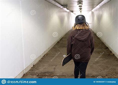 Teen Girl Walking Through A Tunnel With Her Skateboard Stock Image