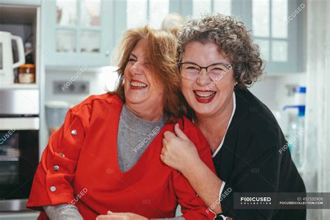 glad middle aged lesbian woman embracing smiling female beloved in house — bright home stock