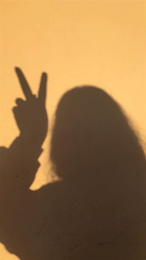 The Shadow Of A Person Holding Their Hand Up In The Air With One Peace Sign