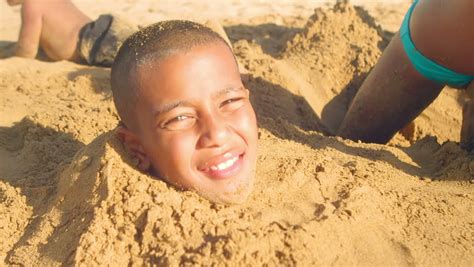 A Young Boy And Girl Smile While They Are Buried In Sand