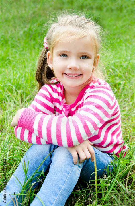 Cute Smiling Little Girl Lying In Grass On The Meadow Stock Photo