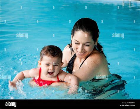 Beautiful Mother Teaching Cute Baby Girl How To Swim In A Swimming Pool