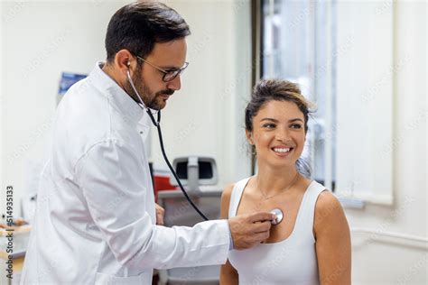 Young Doctor Listen To Female Patient Heart Chest With Stethoscope At