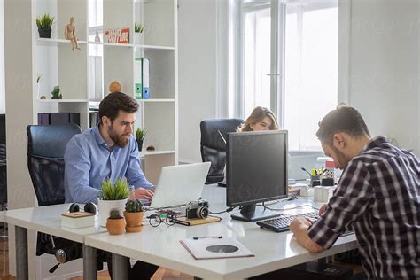 A Group Of People Sitting At Their Desks Working On The Computers In