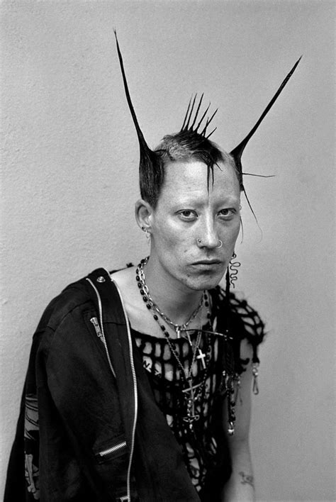 a woman with spikes on her head is posing for a black and white photo in front of a wall