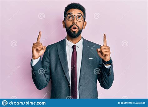 Handsome Hispanic Business Man With Beard Wearing Business Suit And Tie Amazed And Surprised