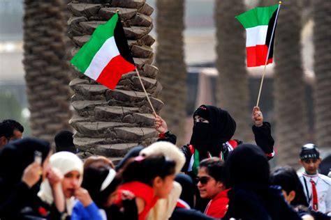 A Woman Waves Two Kuwaiti Flags During A Military Demonstration Held At