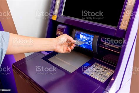 Hand Of Asian Woman Inserting Atm Card Into Purple Atm Machine Stock