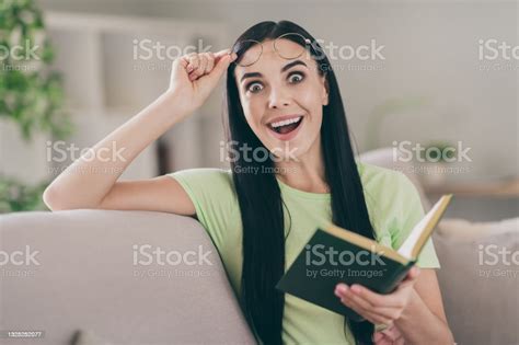 Photo Of Funny Excited Girl Sit Sofa Hold Book Take Off Specs Open