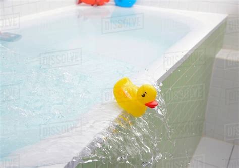 Rubber Duck Falling Out Of Bath Overflowing With Water Stock Photo
