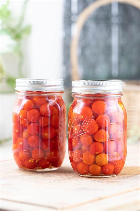 Two Jars Filled With Red And Orange Candies On Top Of A Wooden Table