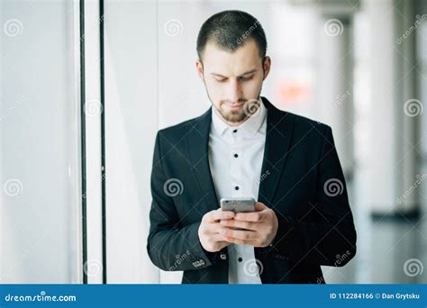 Happy Young Businessman Reading Text Message On Cell Phone At Office
