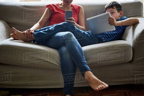 Mother And Son Relaxing On Sofa Using Digital Tablet And Smartphone Stock Photo Dissolve