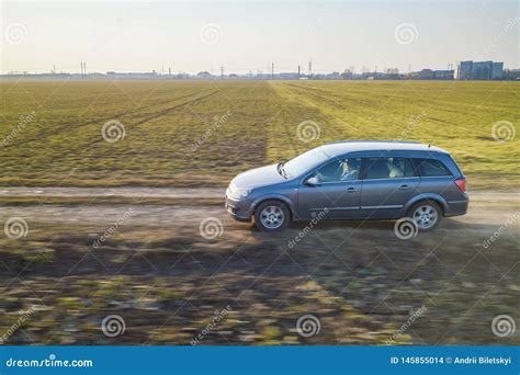 Aerial View Of Car Driving By Straight Ground Road Through Green Fields