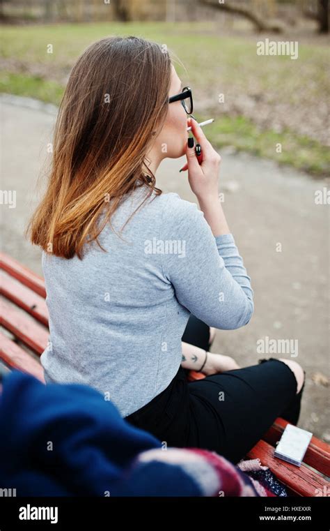 Young Girl Smoking Cigarette Outdoors Sitting On Bench Concept Of