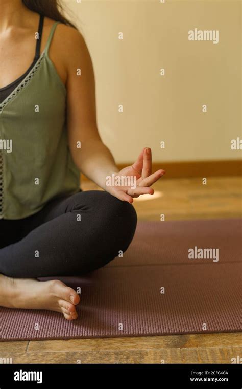 Side View Of Anonymous Female In Sportswear Sitting Barefoot On Floor