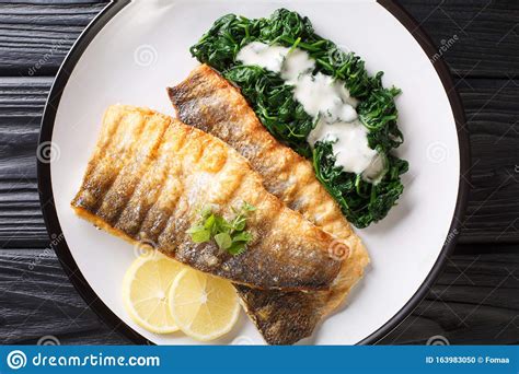 Tasty Grilled Sea Bass Fillet With Spinach And Lemon Close Up On A Plate Horizontal Top View
