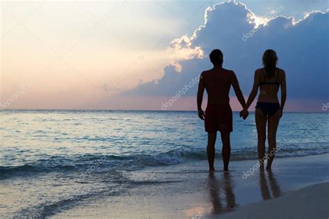 Silhouette Of Couple Walking Along Beach At Sunset ⬇ Stock Photo Image
