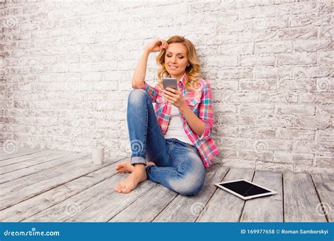 Pretty Woman Sitting On Floor And Typing Message On Mobile Phone Stock