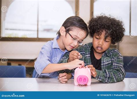 Two Little Boys Putting Money Into Piggy Bank For Future Savings Stock