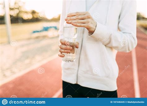 Athletic Girl Holds A Water Bottle While Standing Outdoors In A Stadium