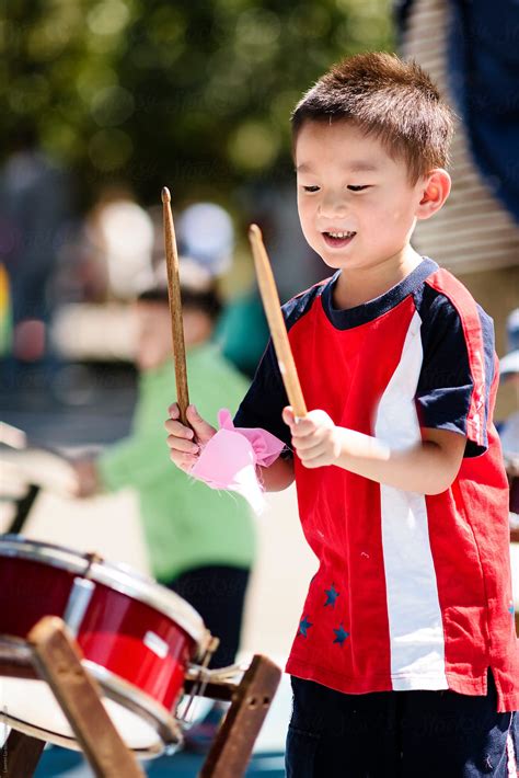 Child Holding Drumstick And Playing Drum In Sunlight By Stocksy