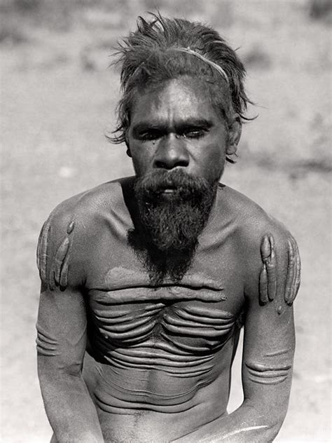 A Man With A Beard And No Shirt Sitting On The Ground In Front Of Him