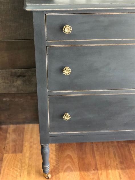 A Grey Dresser With Gold Handles And Knobs