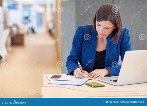 Businesswoman Working On Paperwork At Her Desk In Shared Office Stock