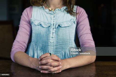 Woman Sitting With Hands Foldded At Table Stock Photo Download Image
