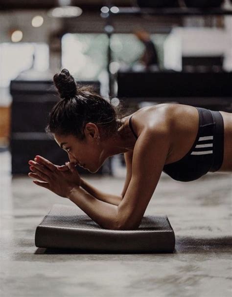 A Woman Doing Push Ups On A Yoga Mat In A Gym Setting With Her Hands