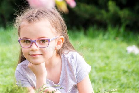 Portrait Of A Six Year Old Girl With Glasses On A Blurred Background Of