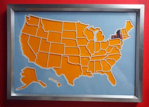 A Framed Map Of The United States In Orange And Blue On A Red Wall With