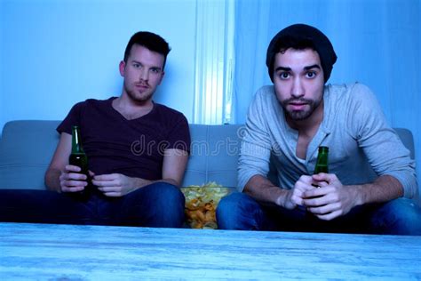 Two Friends Watching Passionately Tv With Beer And Chips Stock Image