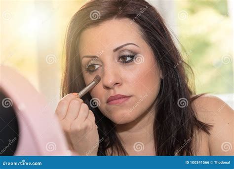 Young Woman Applying Makeup On Her Face Light Effect Stock Photo