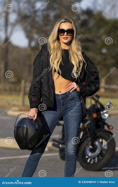 A Lovely Blonde Model Enjoys The Outdoor Weather While Posing With Her Motorcycle Stock Image