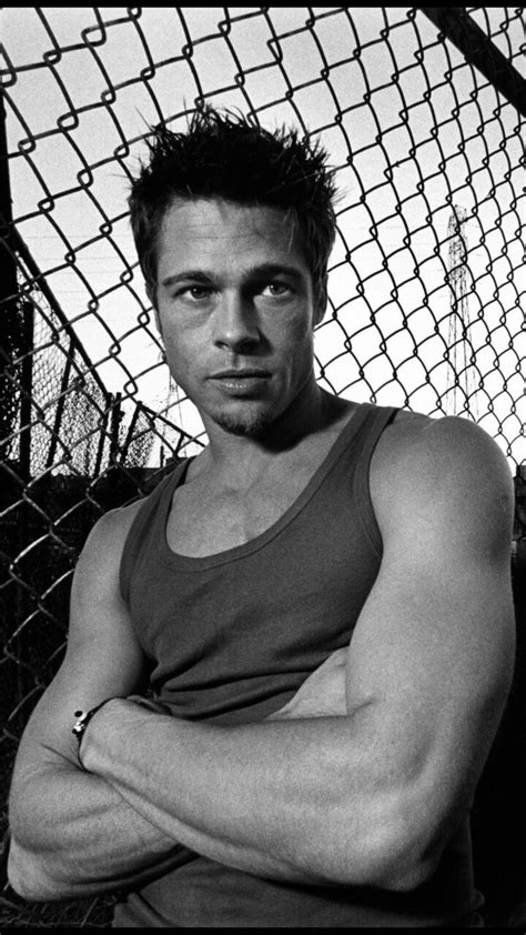 A Black And White Photo Of A Man Leaning Against A Fence With His Arms