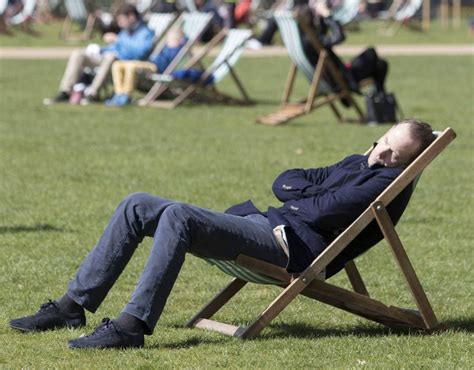 A Man Falls Asleep In A Deck Chair At Hyde Park In London In The Warm