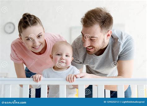 Happy Parents With Infant Boy In Baby Crib Stock Photo Image Of