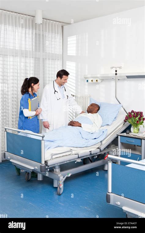 A Doctor And Nurse Talking To A Patient Lying In A Hospital Bed Stock