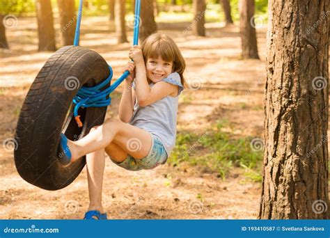 Happy Active Child Girl Playing On Swing Wheel In Forest On Sunny