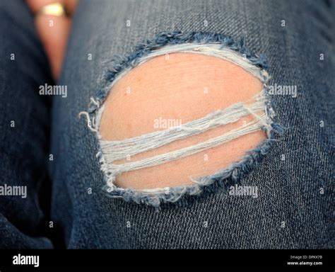 Denim Jeans Being Worn With A Large Hole In The Knee Stock Photo Alamy