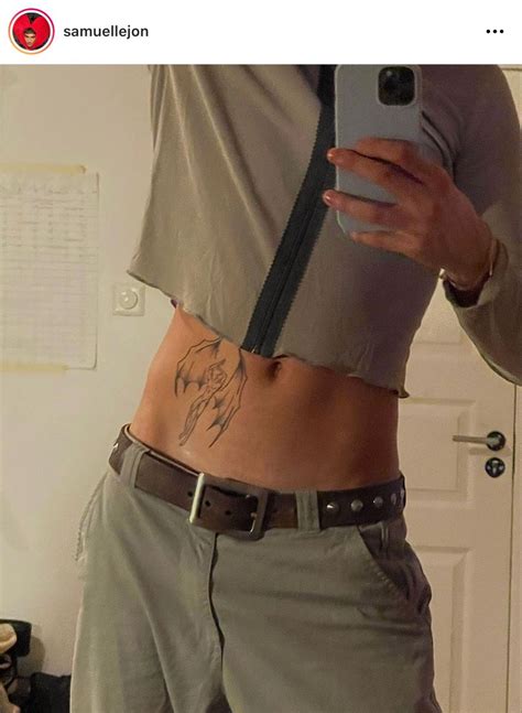 A Person With Tattoos On Their Stomach Holding A Cell Phone And Taking A Selfie