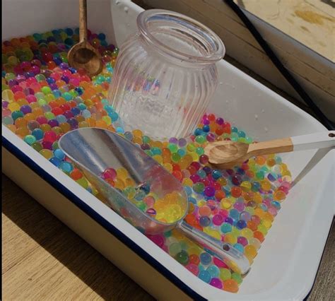 A Container Filled With Lots Of Colorful Beads And Spoons