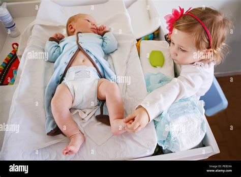 Lifestyle Portrait Of Cute Girl Toddler Helping Her Mother Changing