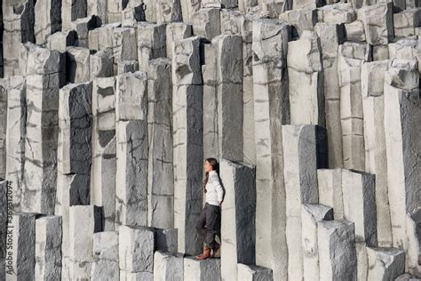Iceland Tourist At Beach Sitting On Basalt Columns On Reynisfjara Beach