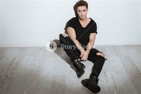 Image Of Young Attractive Man Dressed In Black T Shirt Sitting Over